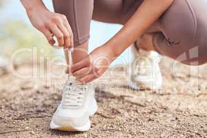 I woke up early with determination. Closeup shot of an unrecognisable woman tying her shoelaces while exercising outdoors.