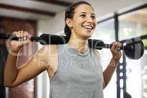 Strength training makes your joints stronger. a sporty young woman exercising with a barbell in a gym.