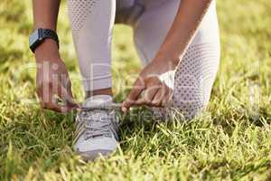 Dont allow yourself to stumble. Closeup shot of an unrecognisable woman tying her shoelaces while exercising outdoors.