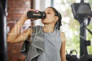That was intense but so worth it. a sporty young woman drinking water while exercising in a gym.