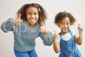 We totally approve. two adorable little girls standing together and showing a thumbs up.