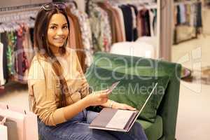 If you dont find what youre looking for in-store, go online. a young woman using her credit card and a laptop while sitting in a boutique.