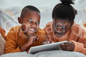 Taking turns to play their favourite games. Portrait of a young boy using a digital tablet with his sister at home.