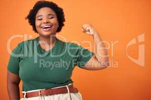 Ive got so much power. a beautiful young woman flexing while standing against an orange background.