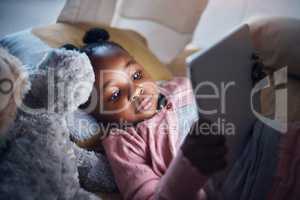 Time for some intense relaxation. a little girl using her digital tablet in her bedroom.