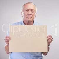 Listen up folks... Studio shot of a senior man holding a blank sign against a grey background.