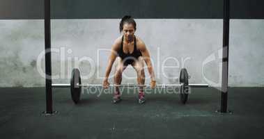 Put in some effort, not excuses. a young woman exercising with a barbell in a gym.