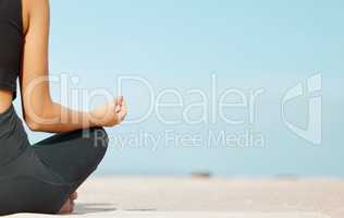 Keep calm and stay calm. Rearview shot of an unrecognisable woman meditating at the beach.