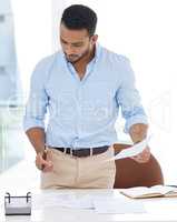 Sorting through a pile of paperwork. a young businessman going through paperwork in an office.