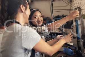 A tomboy is the heart of every princess. two young female workers fixing a bike at a bicycle repair shop.