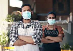 Your health comes first. two young restaurant owners standing outside together with her arms folded while wearing face masks.