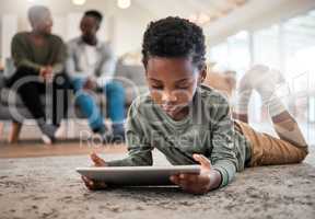 One little device, lots of awesome apps. an adorable little boy using a digital tablet with his family in the background at home.