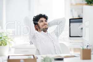 Finally, a chance to rest and reap my rewards. a young businessman sitting with his hands behind his head while working in an office.