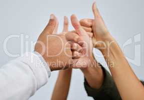 Now thats something we all agree on. Closeup shot of a group of people showing thumbs up together against a white background.
