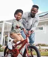 Developing lifelong skills while having tons of fun. Portrait of an adorable boy learning to ride a bicycle with his father outdoors.