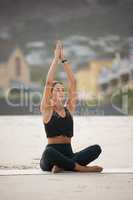 Feel the calm flow through you. a young woman meditating while practising yoga at the beach.