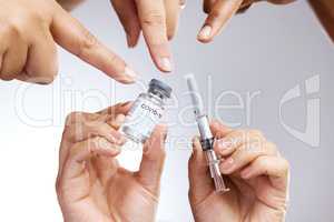 This is essential to your survival and your well-being. Studio shot of a group of people showing thumbs up and holding the vaccine against a grey background.