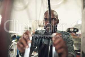 This needs to be nice and tight. a handsome young man standing alone in his shop and repairing a bicycle wheel.