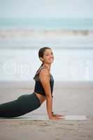 Doing a little yoga each day makes a big difference. Portrait of a young woman doing a cobra stretch while exercising at the beach.