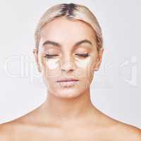 The fountain of youth is store bought. Studio shot of a beautiful young woman wearing an under-eye beauty patch against a grey background.