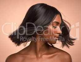 Shine a light. a young attractive woman tossing her hair against a brown background.