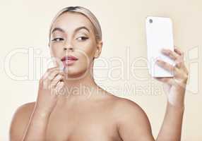 I dont promote anything I dont love myself. a woman looking into her cellphone while applying lipstick.