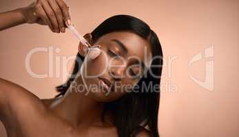 Love today, no hate for tomorrow. an attractive young woman using a derma roller against a brown background.