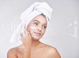 So soft id caress it myself. Studio shot of a beautiful young woman applying moisturiser against a grey background.