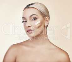 Choose the right makeup for your skin. Studio shot of a woman posing with different shades of makeup on her cheek.