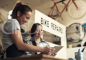 Joy travels by laughter. two young women using a digital tablet at work.