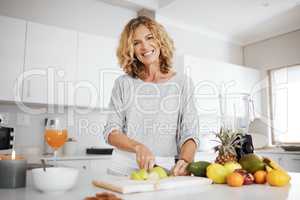 Fill yourself with nutrients. a woman cutting up fruit for a smoothie.