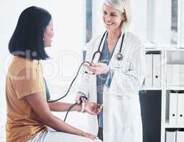 Your pressure is well within the normal range. a doctor examining a woman with a blood pressure gauge.