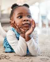 Little girl, big dreams. an adorable little girl liyng on the floor at home and looking thoughtful.