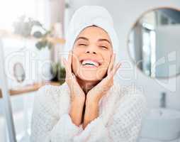 Feeling joy from the inside out. a young woman applying moisturiser to her skin in her bathroom.