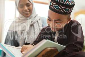 Education is the lighting of a fire. a young muslim mother and her son reading in the lounge at home.