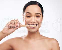 Taking care of your teeth helps you to smile more confidently. Studio shot of a beautiful young woman brushing her teeth while standing against a white background.