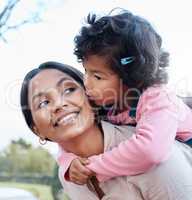 Nothing melts my heart like a kiss from my daughter. a woman carrying her daughter on her back while standing outside.