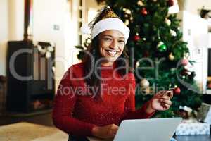 Christmas shopping just got so much easier. a happy young woman using a laptop and credit card during Christmas at home.