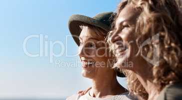 Taking in the views. two attractive mature women standing on the beach.