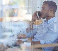 He knows how to get business done. a young businessman talking on a cellphone in an office.