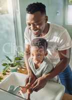 A clean nation starts at home. a father helping his son wash his hands at a tap in a bathroom at home.