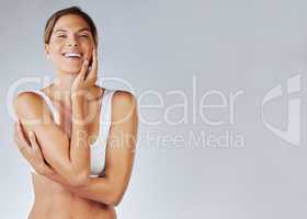 Happiness is infectious. a young woman admiring her complexion against a studio background.