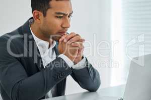Spirit not broken, wiser than before. a businessman looking worried while using his laptop at his desk in a modern office.