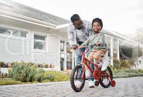 Dad will always be there to support him. Portrait of an adorable boy learning to ride a bicycle with his father outdoors.