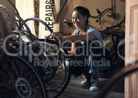 Imagine needing someone to do this for me. a young happy young woman fixing a bike at a bicycle repair shop.