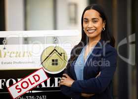 Let me find the perfect home for you. Cropped portrait of an attractive young real estate agent standing with her arms crossed next to a sold sign outside of a recently sold home.