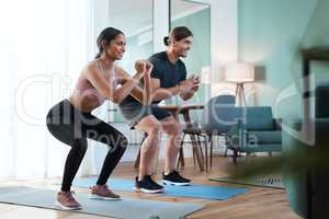 Squat squad. Full length shot of an athletic young couple squatting on an exercise mat during their workout at home.