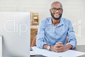 Even when youve reached your goals, keep pushing just as hard. Portrait of a businessman smiling while sitting at his desk.