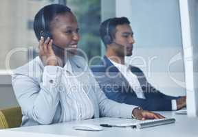 On a mission to help. two young call center agents working at their desks in the office.