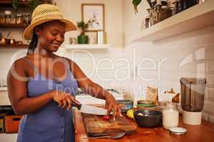 Somebody wife me already. a young beautiful woman wearing a sunhat while slicing fruit in the kitchen at home.